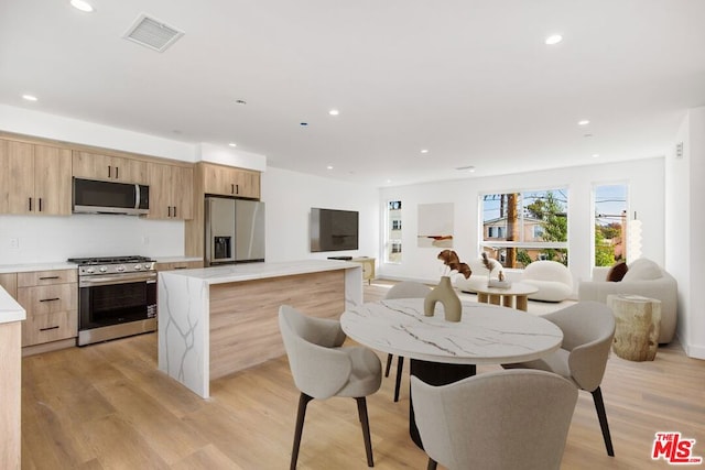 kitchen featuring light hardwood / wood-style floors, light brown cabinetry, appliances with stainless steel finishes, and a kitchen island