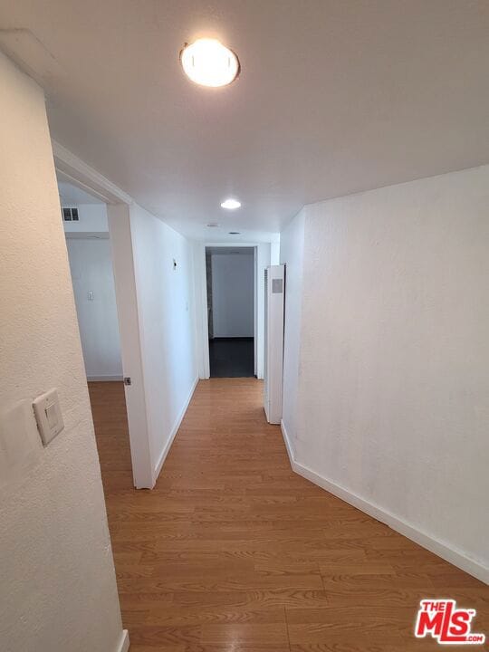 corridor with hardwood / wood-style flooring