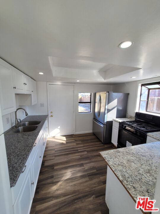 kitchen with gas stove, sink, white cabinets, dark hardwood / wood-style flooring, and stone countertops