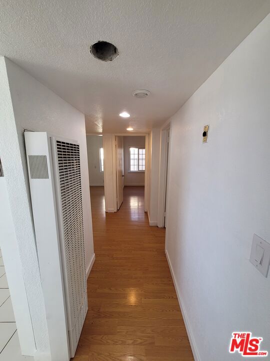 hall with light wood-type flooring and a textured ceiling