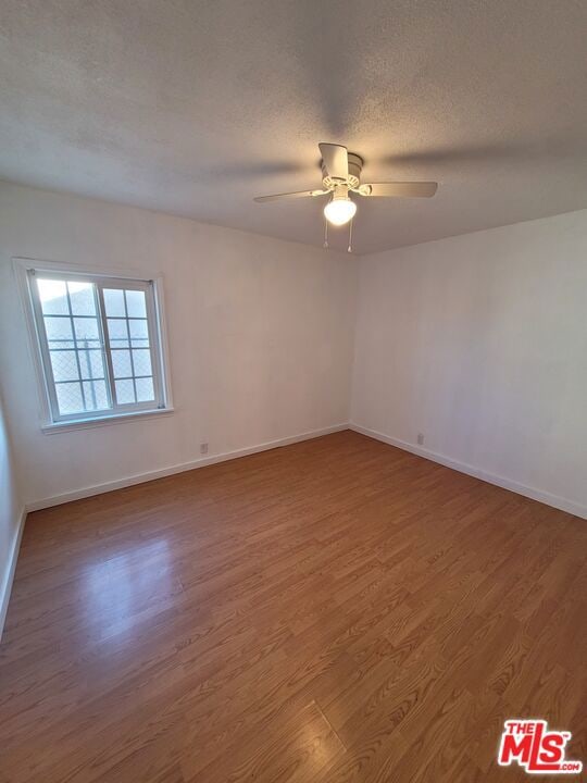 spare room with a textured ceiling, ceiling fan, and hardwood / wood-style flooring