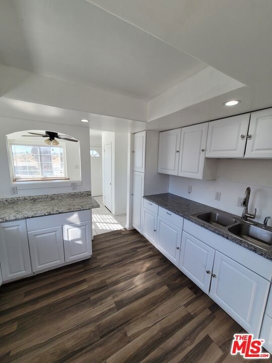 kitchen with ceiling fan, dark hardwood / wood-style floors, dark stone countertops, sink, and white cabinets