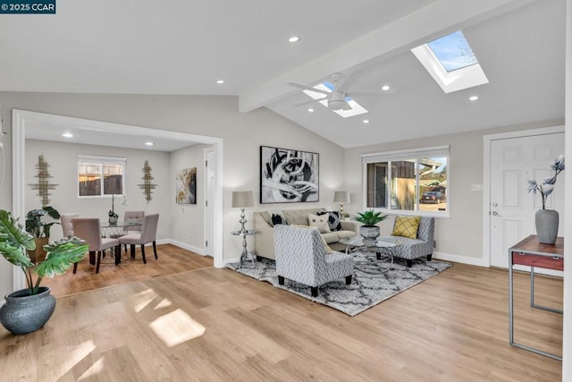 living room featuring light wood-type flooring, ceiling fan, plenty of natural light, and vaulted ceiling with skylight