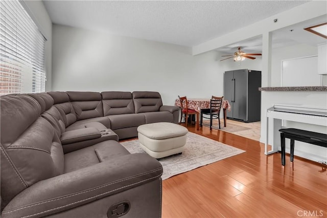 living room featuring a textured ceiling, ceiling fan, and light hardwood / wood-style floors