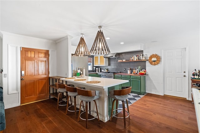 kitchen featuring a breakfast bar, kitchen peninsula, decorative backsplash, appliances with stainless steel finishes, and green cabinetry