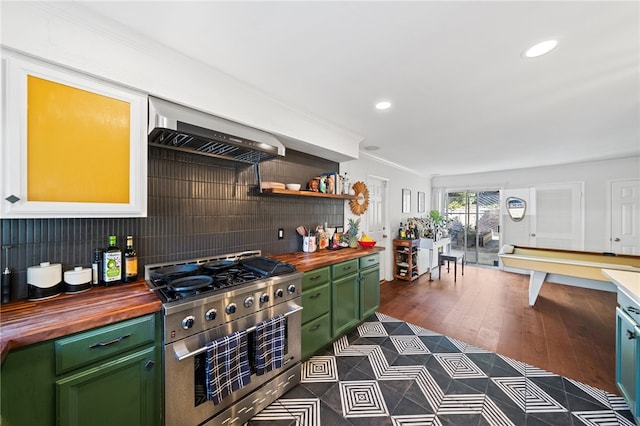 kitchen with high end stove, decorative backsplash, butcher block countertops, green cabinetry, and wall chimney exhaust hood