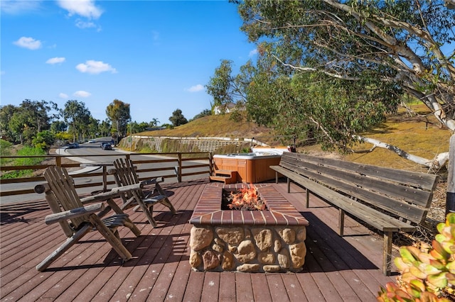 deck featuring an outdoor fire pit and a hot tub