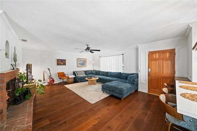 living room featuring dark wood-type flooring, a brick fireplace, ornamental molding, and ceiling fan