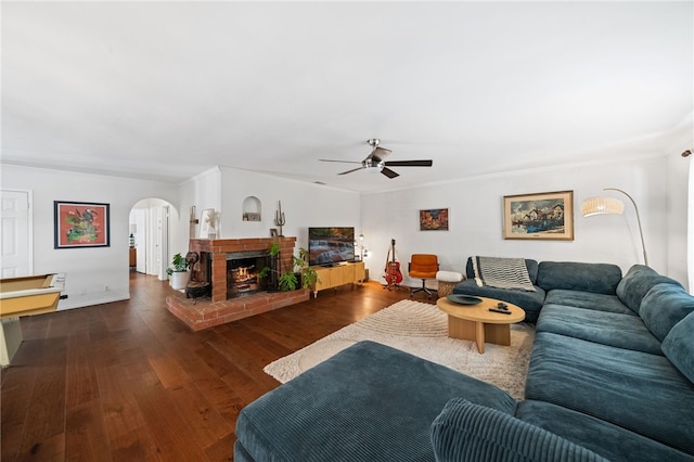 living room with dark wood-type flooring, a fireplace, and ceiling fan