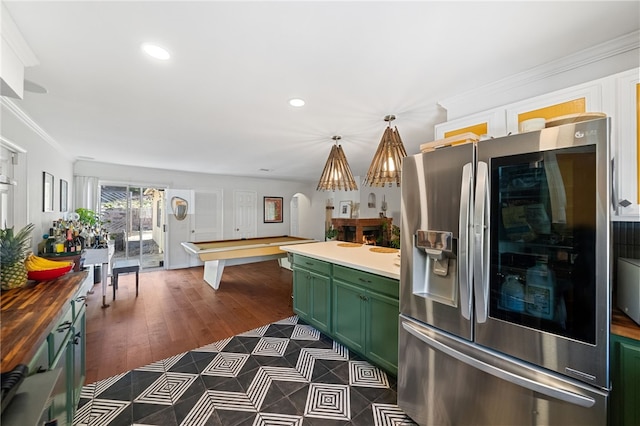 kitchen featuring ornamental molding, butcher block counters, green cabinetry, and stainless steel refrigerator