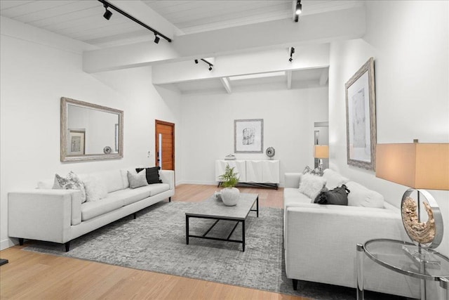 living room with rail lighting, hardwood / wood-style floors, and beam ceiling