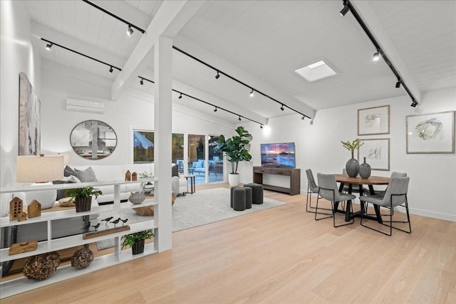 living room featuring rail lighting, lofted ceiling with skylight, a wall mounted air conditioner, and light hardwood / wood-style floors