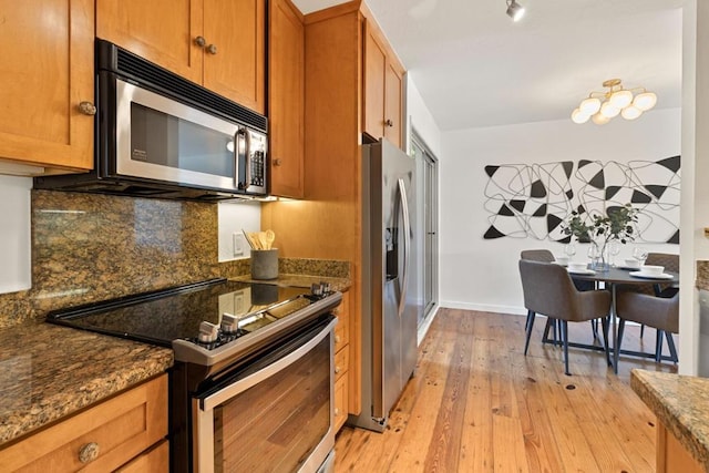 kitchen featuring tasteful backsplash, appliances with stainless steel finishes, dark stone counters, and light hardwood / wood-style flooring