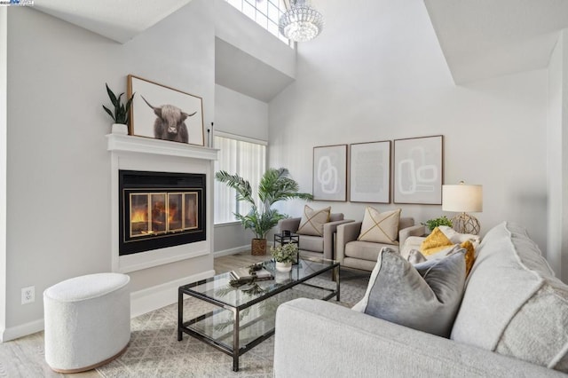 living room with a chandelier, light hardwood / wood-style floors, and a towering ceiling