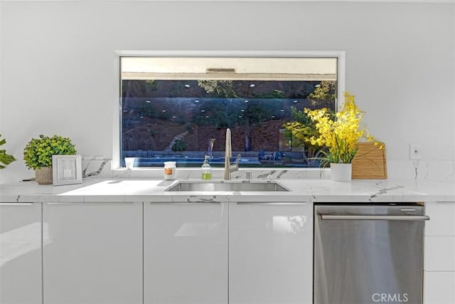 interior space featuring light stone counters, white cabinets, sink, and dishwasher