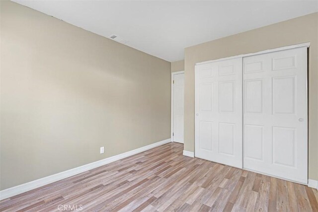 unfurnished bedroom with a closet and light wood-type flooring