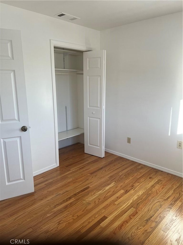 unfurnished bedroom featuring a closet and hardwood / wood-style flooring