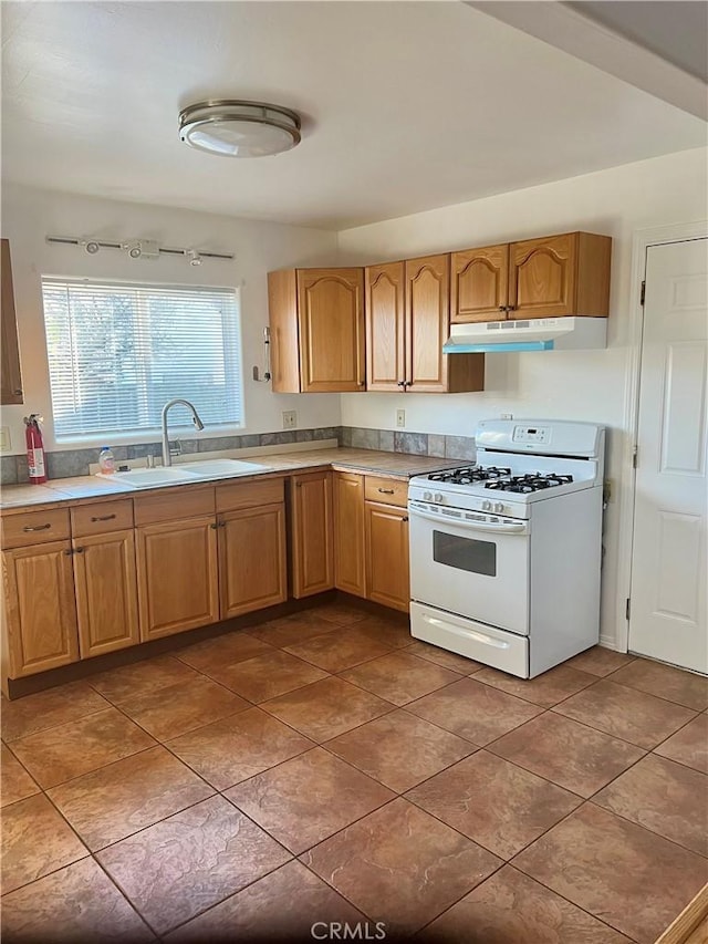 kitchen with dark tile patterned flooring, sink, and white range with gas cooktop