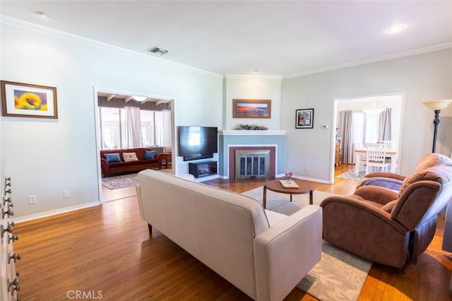 living room featuring crown molding, a fireplace, and light hardwood / wood-style flooring