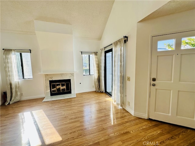 entrance foyer featuring lofted ceiling, a textured ceiling, a fireplace, and light hardwood / wood-style floors