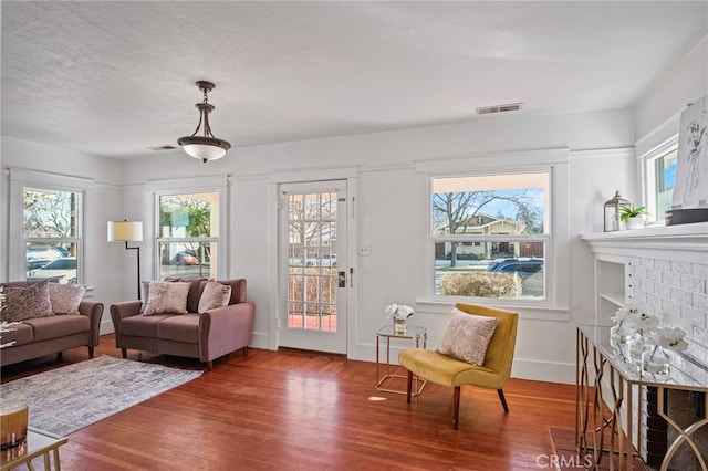 living room with a healthy amount of sunlight, wood-type flooring, a fireplace, and built in shelves