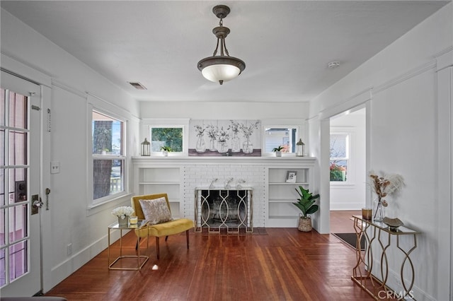 living area with dark wood-type flooring and a brick fireplace