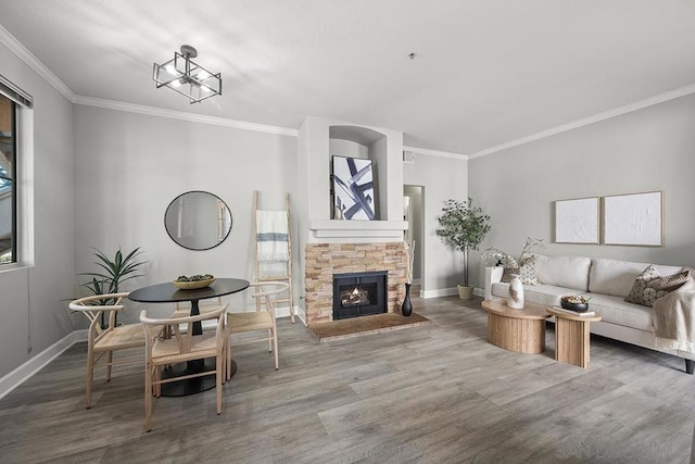 living room with crown molding, a stone fireplace, and hardwood / wood-style floors