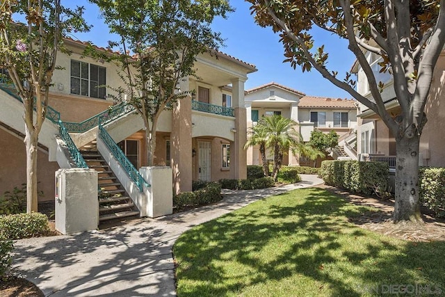 view of front of property featuring a front yard and a balcony