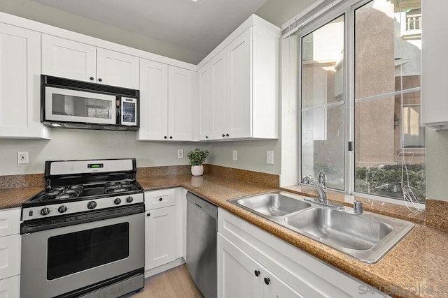 kitchen featuring appliances with stainless steel finishes, sink, white cabinetry, and light hardwood / wood-style floors