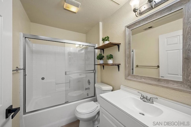 full bathroom with a textured ceiling, combined bath / shower with glass door, toilet, and vanity