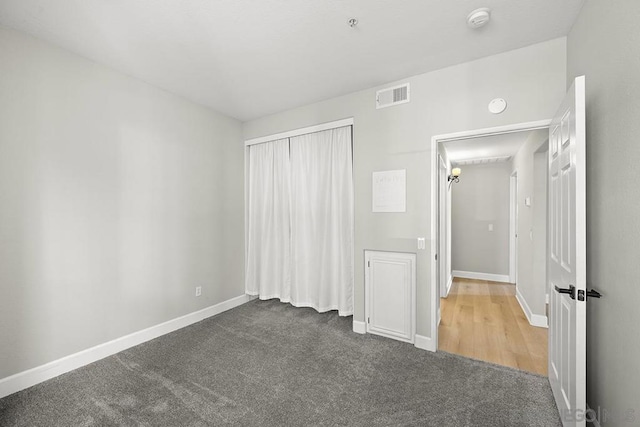 unfurnished bedroom featuring a closet and dark colored carpet