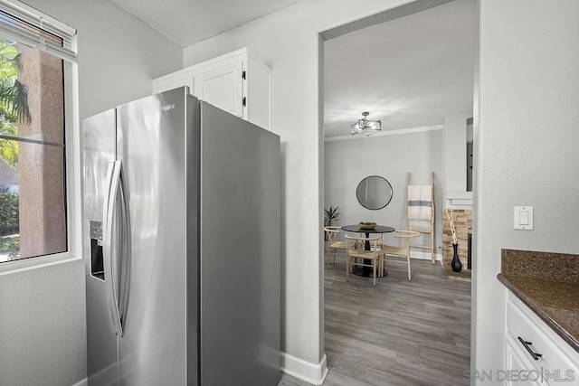 kitchen with stainless steel refrigerator with ice dispenser, white cabinetry, a healthy amount of sunlight, and light hardwood / wood-style flooring