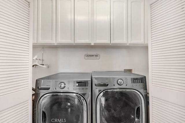 clothes washing area featuring washer and clothes dryer and cabinets