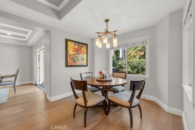 dining area with light hardwood / wood-style floors, a tray ceiling, and a chandelier