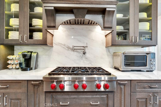 kitchen with stainless steel gas stovetop, dark brown cabinets, and tasteful backsplash