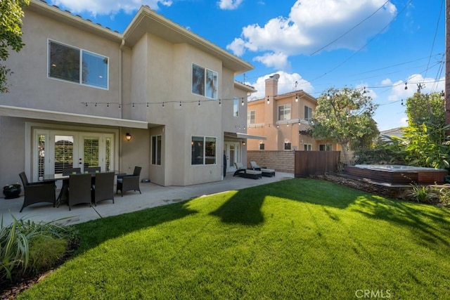 rear view of house with a lawn, french doors, a hot tub, and a patio