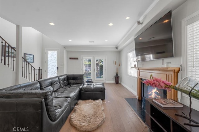 living room with ornamental molding, french doors, and light wood-type flooring