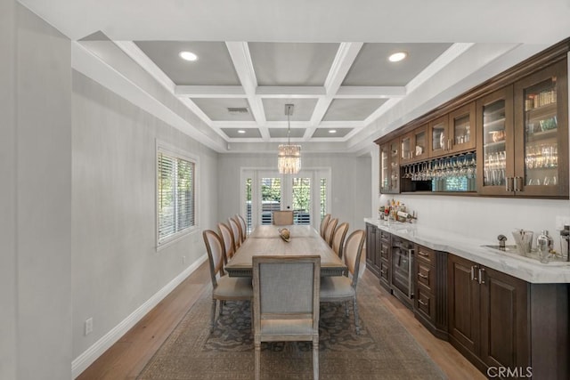 dining space with coffered ceiling, dark wood-type flooring, french doors, bar area, and beamed ceiling