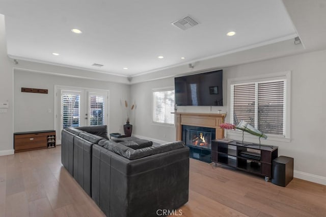 living room with light hardwood / wood-style floors, ornamental molding, and french doors