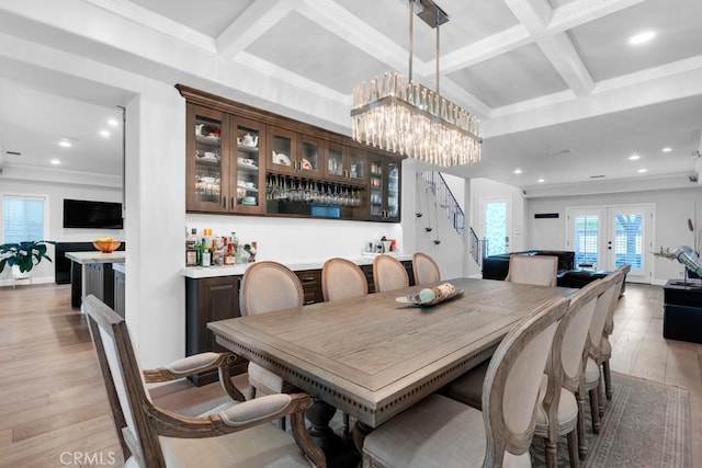 dining area with french doors, light wood-type flooring, bar area, crown molding, and coffered ceiling