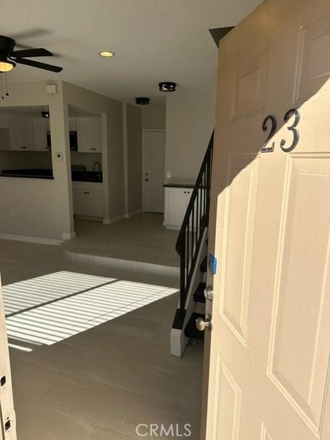 staircase with ceiling fan and tile patterned floors