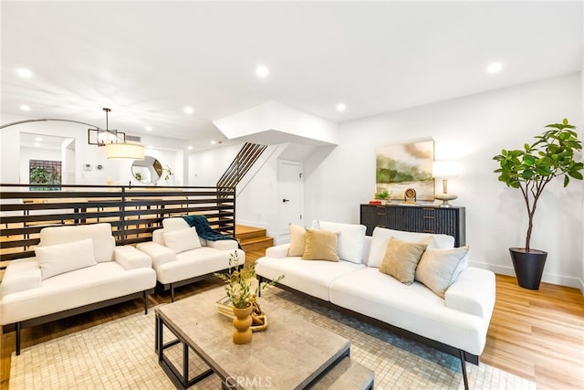 living area featuring baseboards, light wood-style flooring, stairs, a chandelier, and recessed lighting