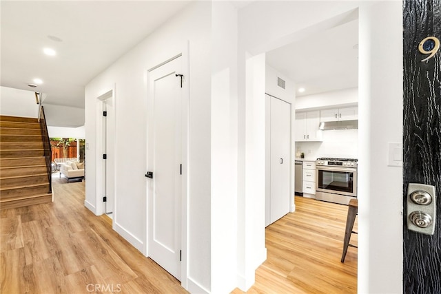 corridor with light wood finished floors, visible vents, stairway, and recessed lighting