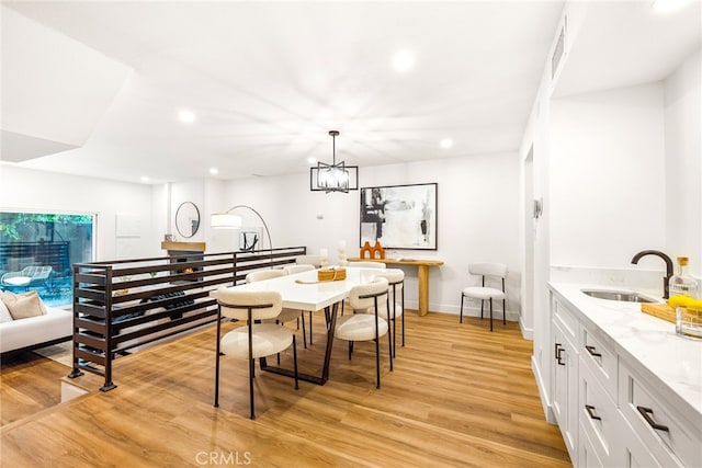 dining room featuring light wood-type flooring, baseboards, a chandelier, and recessed lighting