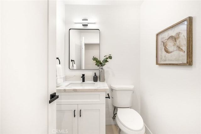 bathroom with baseboards, vanity, and toilet