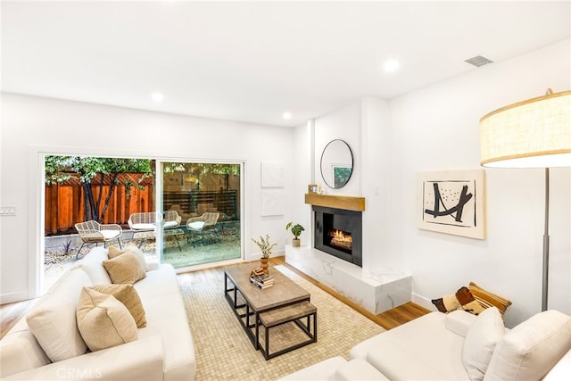 living area with a high end fireplace, baseboards, recessed lighting, and wood finished floors