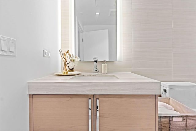 bathroom with tile walls, toilet, and vanity