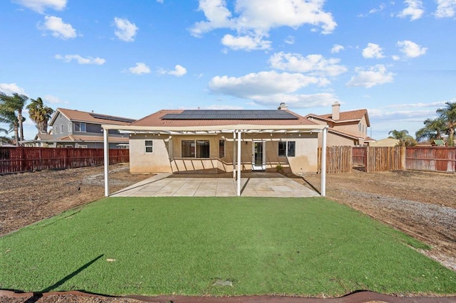 back of property with a yard, a patio area, and solar panels