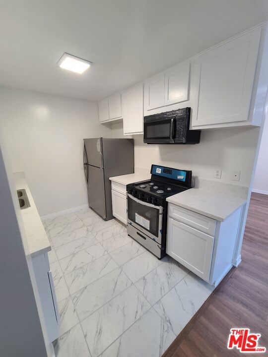 kitchen with sink, white cabinets, and black appliances