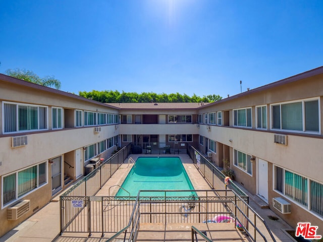 view of pool with a wall unit AC and a patio